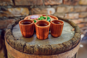 Naklejka premium grappa glass on an oak barrel. strong alcoholic drink grappa in a ceramic glass, with a snack