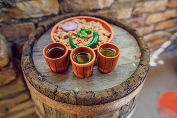 grappa glass on an oak barrel. strong alcoholic drink grappa in a ceramic glass, with a snack