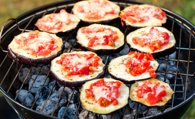Eggplant with tomato and parmesan cheese on BBQ vegan grill.