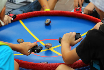 Boys playing popular game beyblade with special spinning tops at the central park.