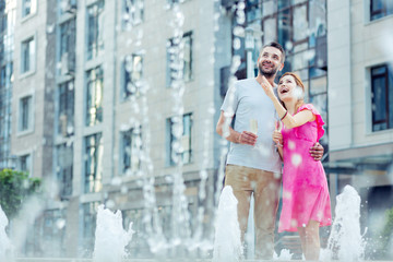 Look how beautiful. Happy cheerful woman smiling while pointing at the fountain