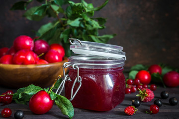 homemade jam in a glass jar of various berries and plums on a dark  background.Healthy food, diet, detox, clean eating and vegetarian concept with copy space.