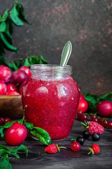 homemade jam in a glass jar of various berries and plums on a dark  background.Healthy food, diet, detox, clean eating and vegetarian concept with copy space.
