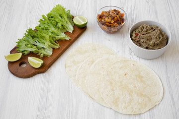 Shrimp tacos ingredients on white wooden table, side view.