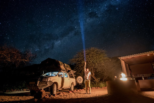 Young male traveler using flashlight crossing the southern milky way at campsite in Namibia, Africa. Road trip travel with stargazing concepts - Powered by Adobe