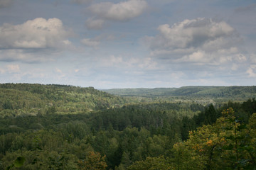 Landscape view on forests tops and blue sky with clouds in background