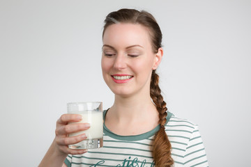 Junge Frau freut sich über ein Glas Milch in der Hand