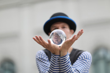 Transparent magic ball with reflection in the open palms of the clown