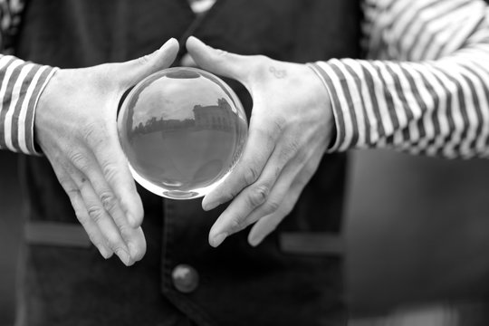 Transparent magic ball with reflection in the hands of a clown