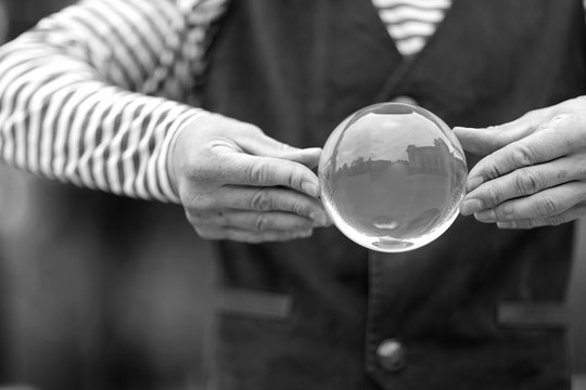 Transparent magic ball with reflection in the hands of a clown