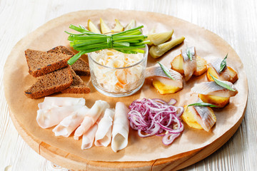 Sandwich on fried potatoes with herring, green onion. Tasty appetizer with sauerkraut, pickled cucumber, mustard on wooden Board. Rye bread and lard