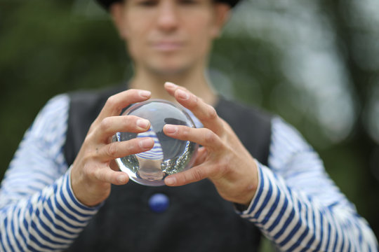 Transparent magic ball with reflection in the hands of a clown