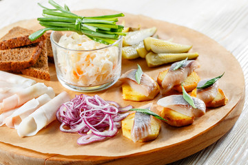 Sandwich on fried potatoes with herring, green onion. Tasty appetizer with sauerkraut, pickled cucumber, mustard on wooden Board. Rye bread and lard