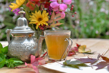 cup of tea on a table with  colorful flowers and leaves on a table in a garden