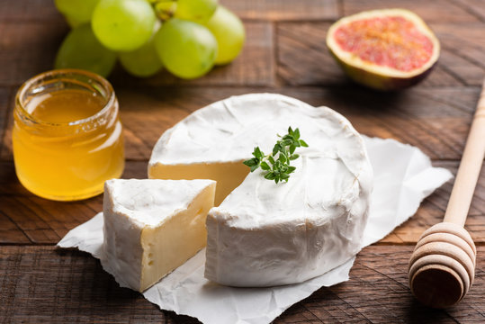 Brie or camembert cheese with figs, grapes and honey on wood