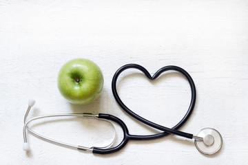 Alternative medicine healthy  sign concept with stethoscope heart and green apple on white...