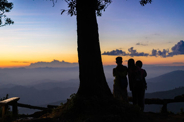 Family Silhouette standing and watching the sunset on the mountain. family relax at the mountain and enjoying a beautiful sunset.