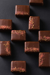 Luxury handmade bonbons decorated with pink salt on black background