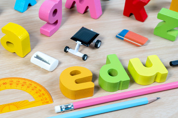 Elementary classroom table with wooden word EDU and education supplies for school background. School objects for Education.