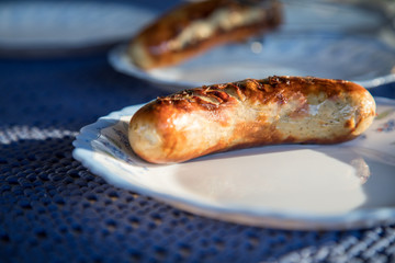Deftige Schweinefleisch Bratwurst vom Grill und Porzellan Teller auf Garten Terrasse 