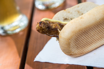 Schweinefleisch Bratwurst vom Grill mit Senf im Weizen Brötchen und Bier im Biergarten