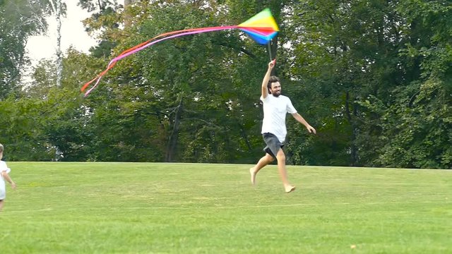 Family weekend. Father running with kite. Summer time. Slowmotion.
