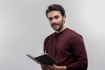 Young intern. Young handsome bearded intern making some notes working in lawyer office on image...