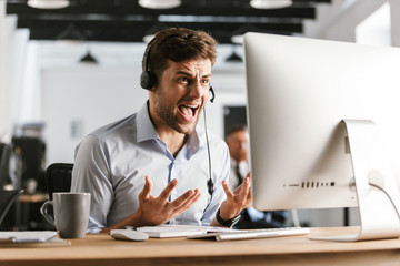 Displeased office manager screaming by headset with microphone