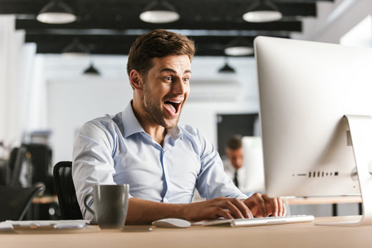 Happy screaming business man using computer and rejoices