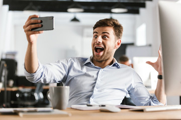 Naklejka na ściany i meble Surprised happy business man making selfie on smartphone