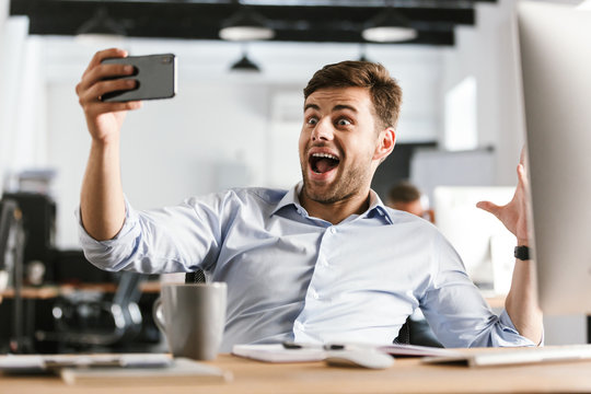 Surprised happy business man making selfie on smartphone