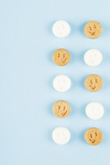 White and brown sugar smiles on blue background. Top view, copy space. Food background