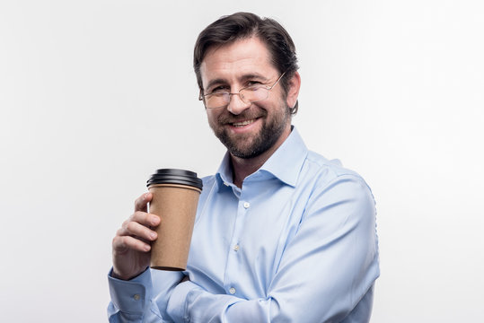 Takeaway coffee. Image without face retouching with bearded man wearing glasses holding takeaway coffee having break