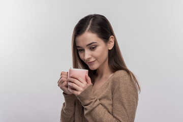 Drinking coffee. Beautiful dark-haired woman feeling relaxed drinking cup of coffee on image...