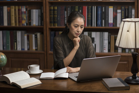 Elegant mature woman using laptop in study