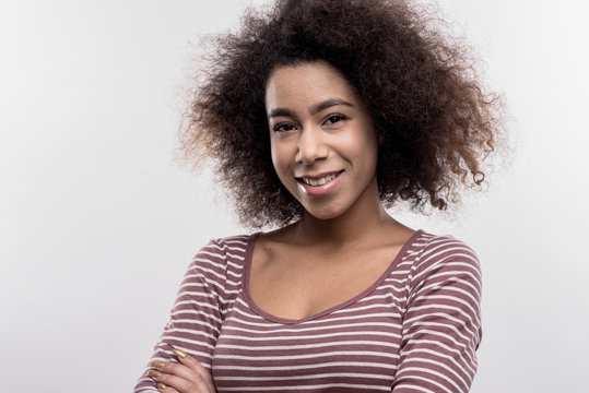 Beaming woman. Image without face retouching with beaming curly dark-haired woman wearing plain striped shirt