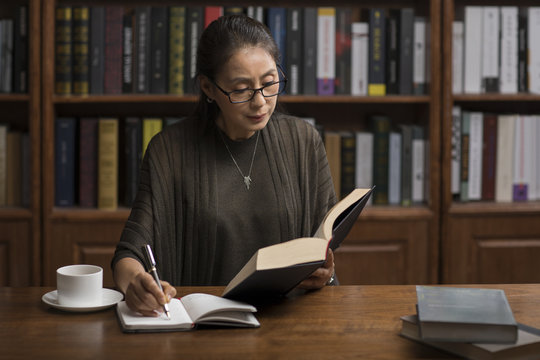 Elegant mature woman reading book in study