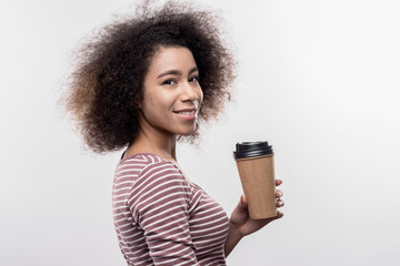 Tasty cappuccino. Dark-eyed curly woman enjoying tasty cappuccino during break on image without...