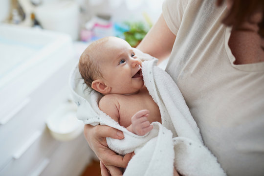 Mother holding baby wrapped in towel after bath