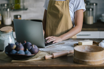 Fototapeta na wymiar cropped shot of woman using laptop during pie preparation