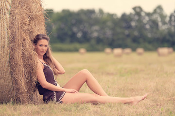 Fototapeta na wymiar Portrait of a beautiful woman with hay bale