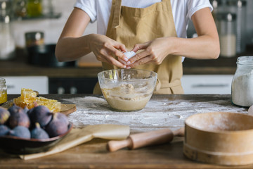 cropped shot of woman breaking egg into bowl during pie preparation