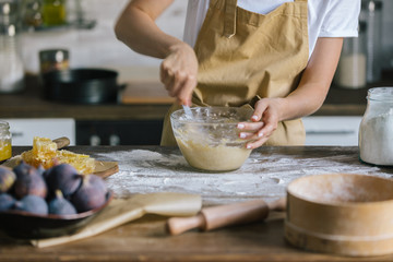 cropped shot of woman mixing dough for pie on rustic wooden table