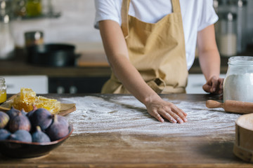 cropped shot of woman covering table with flour for dough preparation