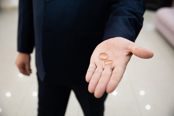 Obraz premium Groom holding gold wedding rings in his hands