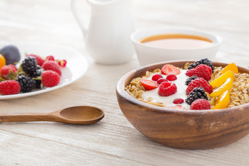 granola with berries on white wooden background