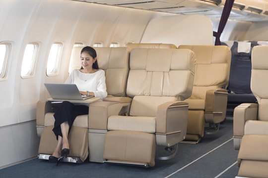 Elegant mature woman using laptop on airplane