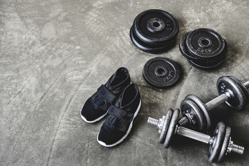 Obraz na płótnie Canvas high angle view of dumbbells with weight plates and sneakers on concrete floor