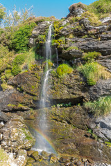 Fototapeta na wymiar Waterfall rio Faro in Redipuertas, Leon (Spain) with a rainbow at the end of it.