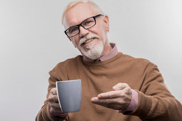 Offering tea. Image without face retouching with kind-hearted aged office manager offering cup of...